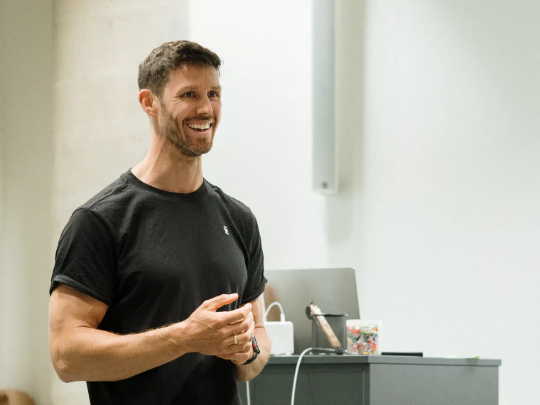 Dom stehend in einem Workshopraum, im Rücken Laptop und Projektion